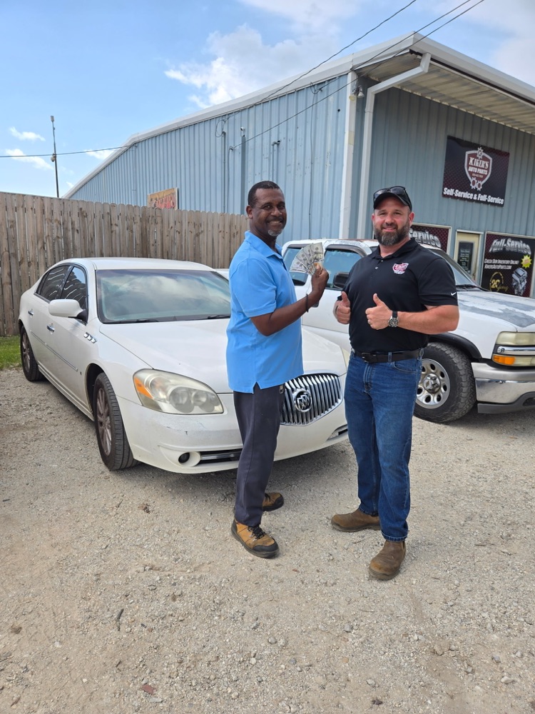 A Kiker's customer receiving cash beside the vehicle he sold